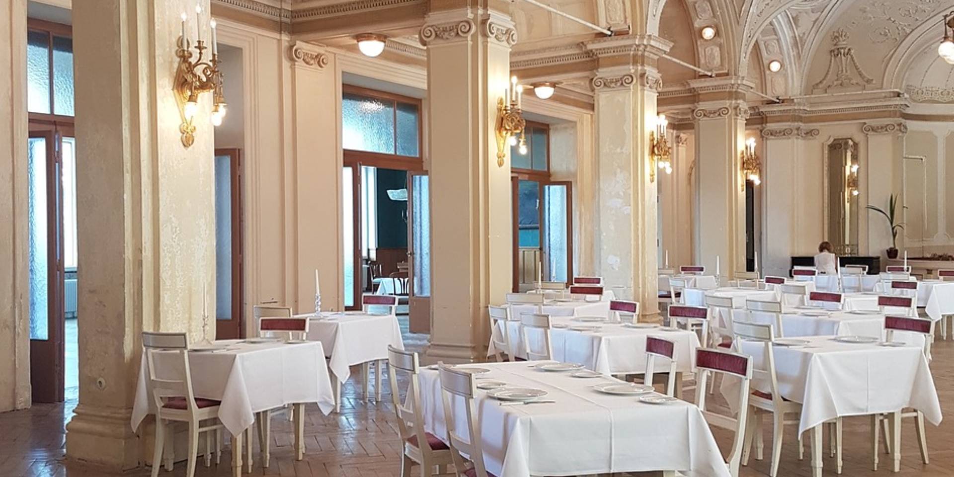 A restaurant with tables and chairs set up for dinner.